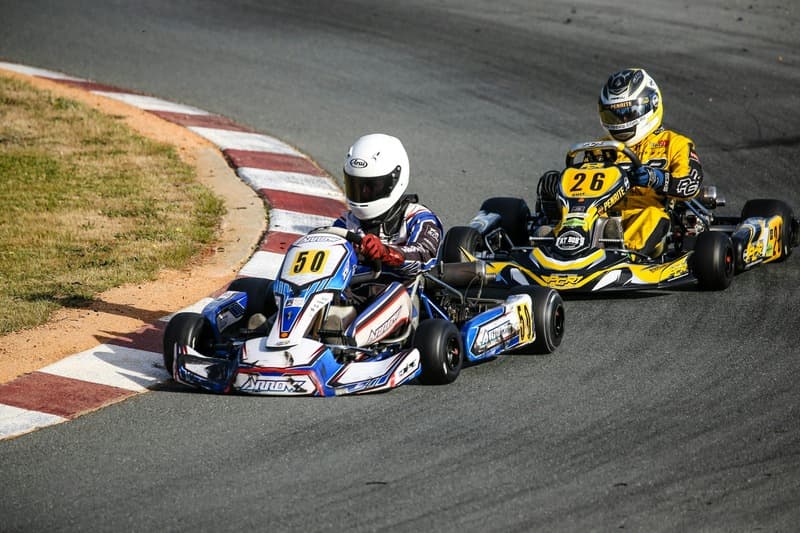 Two karts racing wheel to wheel at Consensus Circuit, the Agents Clan Venture Web3 go karting championship
